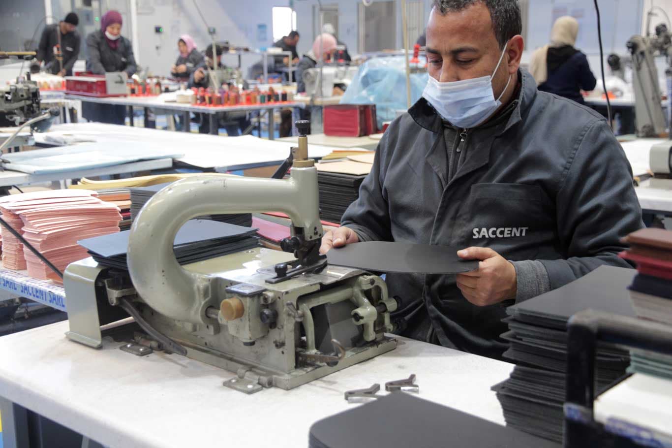 Operator cutting leather panels on a clicking press at Saccent in Fes, Morocco
