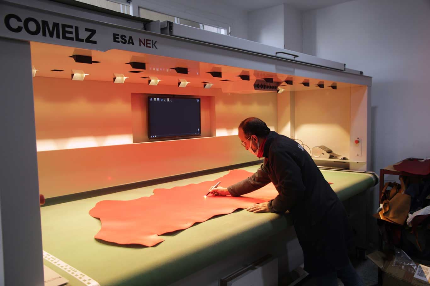 Technician inspecting and marking a hide on a Comelz light table at Saccent, Morocco