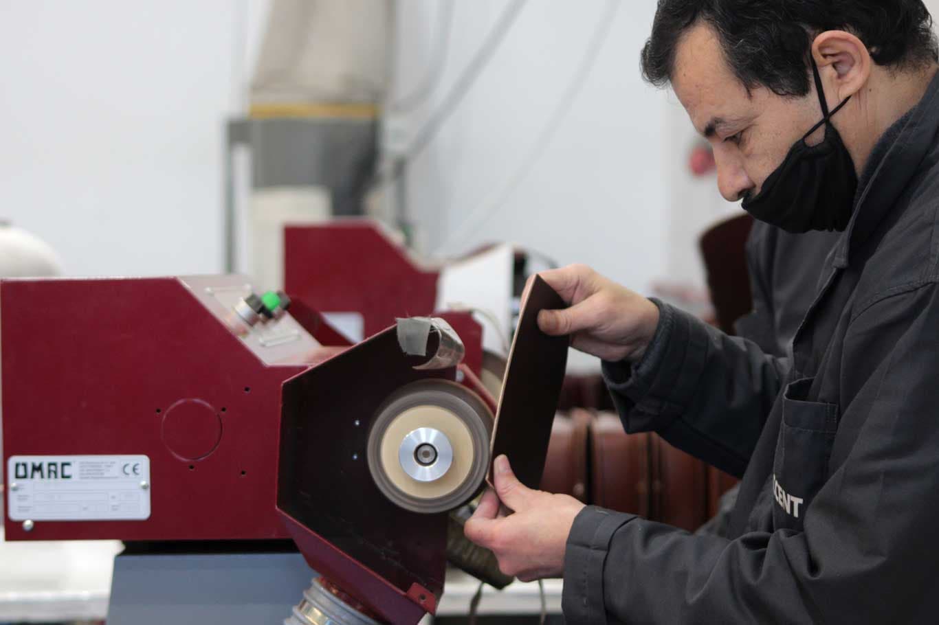 Saccent artisan skiving a leather panel on an OMAC bench machine in Fes, Morocco